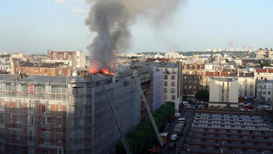 Des pompiers sur une échelle pour tenter d'éteindre l'incendie qui s'est déclaré dans un immeuble résidentiel d'Aubervilliers, en banlieue parisienne, le 7 juin 2014