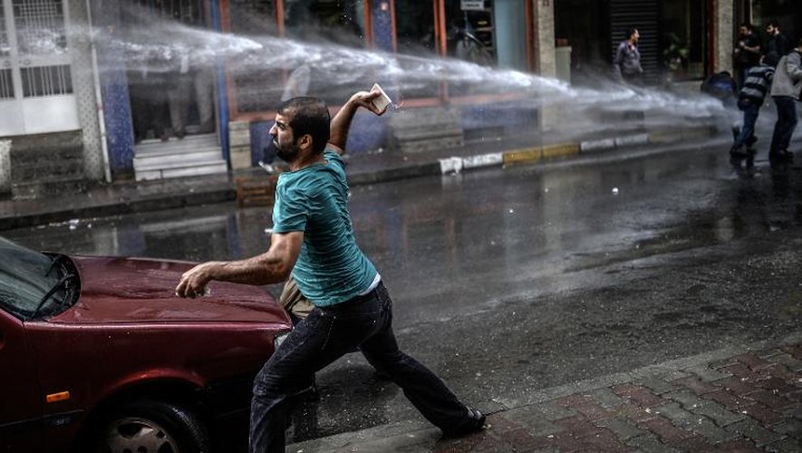 Un militant kurde se heurte aux policiers anti-émeutes turcs lors d'une manifestation le 8 juin 2014, dans le quartier de Bagcilar à Istanbul