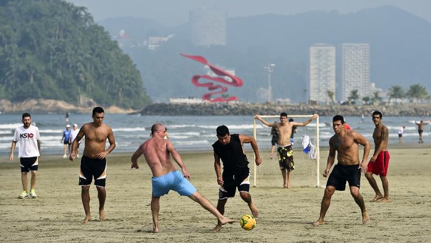 Des personnes jouent au football le 8 juin 2014, sur la plage de Santos, au Brésil, quelques jours avant le début de la Coupe du Monde de foot