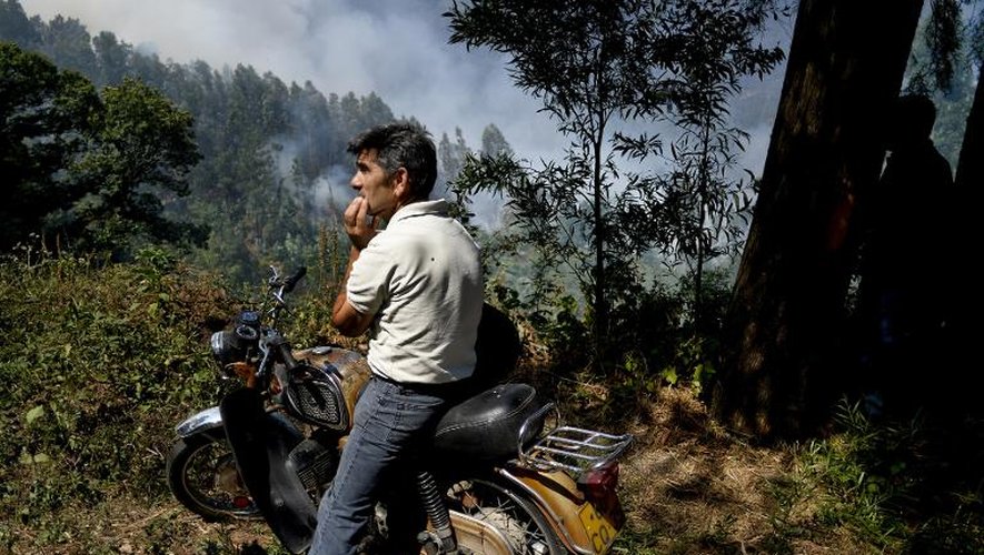 Un homme assis sur sa moto regarde le feu dévaster la forêt près de Caramulo au Portugal le 30 août 2013