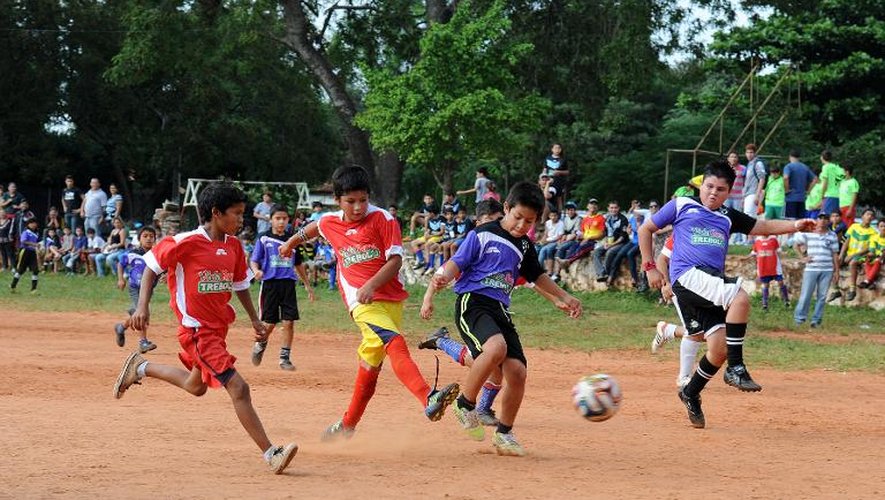Des enfants jouent au football près d'Asuncion le 9 juin 2014