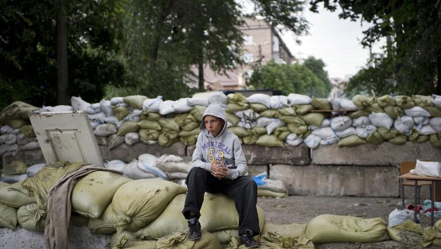 Un jeune homme assis sur une barricade sur le point d'être détruite à Marioupol, le 13 juin 2014
