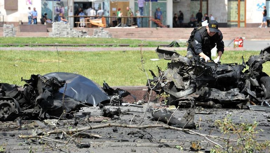 Un policier examine les reste d'un véhicule détruit par une explosion appartenant à Denis Pouchiline, un chef de la rébellion prorusse à Donetsk, dans l'est de l'Ukraine, le 13 juin 2014