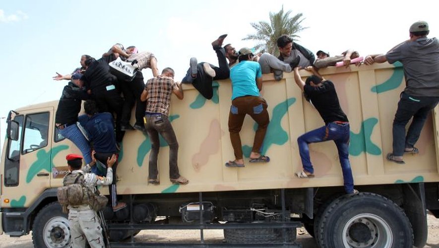 Des volontaires pour combattre les jihadistes grimpent sur un camion de l'armée à Bagdad, le 13 juin 2014