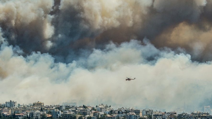 Un hélicoptère vole au-dessus des flammes à Athènes, en proie à un incendie, le 17 juillet 2015