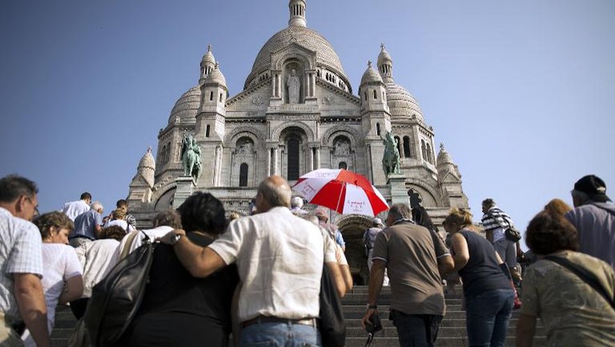 Des touriste face au Sacré Coeur au pied de la butte de Montmartre à Paris, le 10 juillet 2013