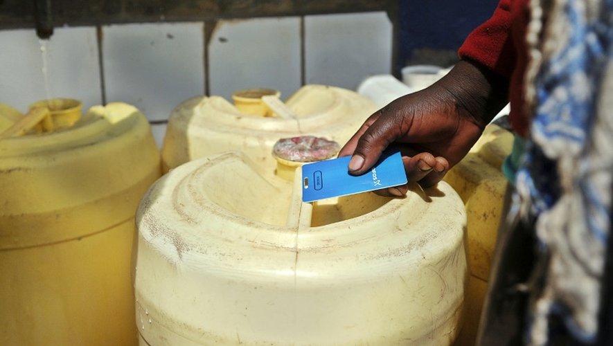 Une femme vient chercher de l'eau dans un distributeur automatique, à l'aide d'une carte rechargeable, dans un bidonville de Nairobi le 24 juin 2015