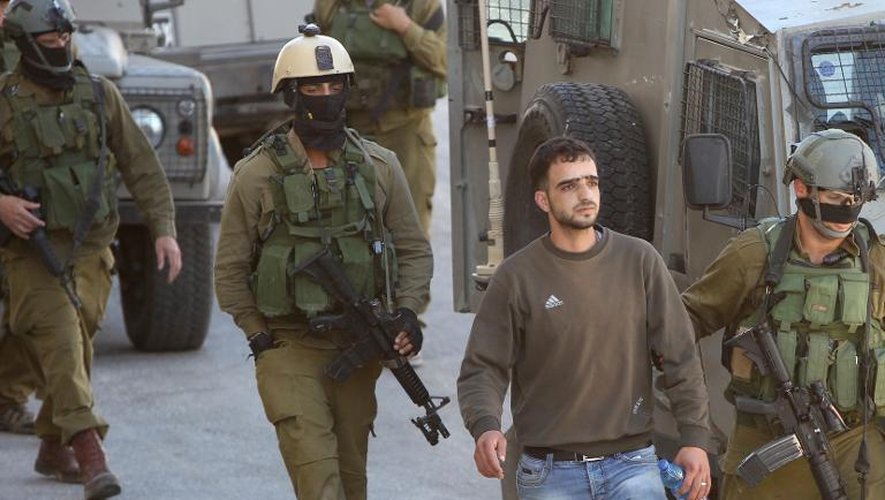 Des soldats israéliens arrêtent un Palestinien à Hébron alors qu'ils cherchent trois jeunes portés disparus en Cisjordanie, le 14 juin 2014