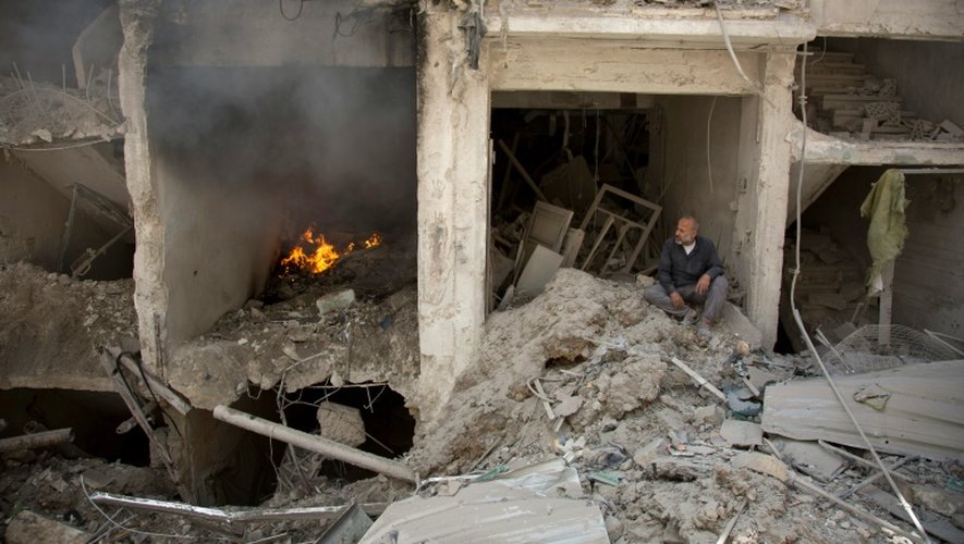 Un homme assis parmi les ruines de bâtiments dévastés le 8 juin 2016 par une frappe aérienne des forces gouvernementales à Alep