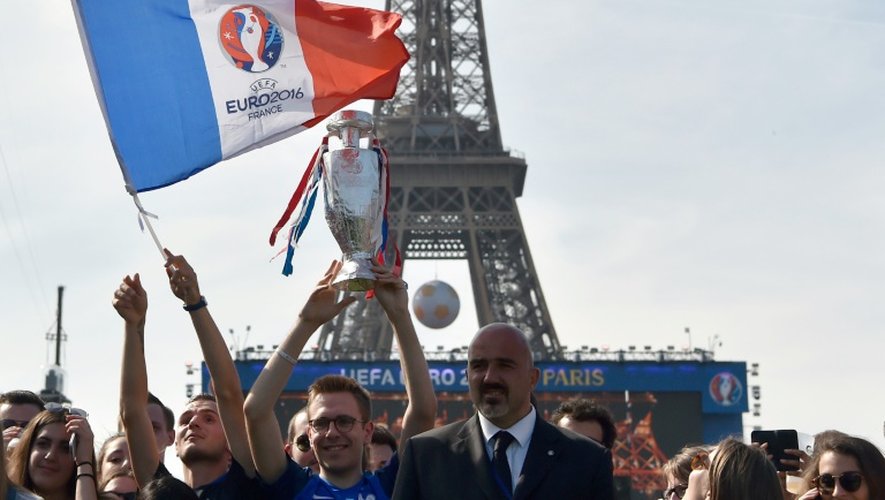 Un supporter tient le drapeau de l'Euro-2016 dans la fan zone au pied de la Tour Eiffel à Paris, tandis que des milliers de personnes se rassemblent pour le concert, le 9 juin 2016