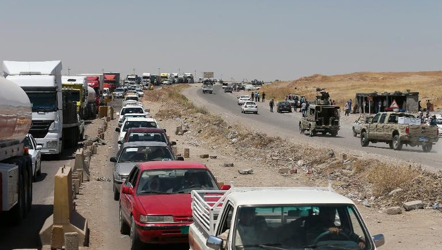 Des familles irakiennes qui fuient à bord de leurs véhicules dans une file d'attente pour passer un poste de contrôle dans la ville al-Muafakiya, à 80 km à l'ouest d'Erbil, le 16 juin 2014
