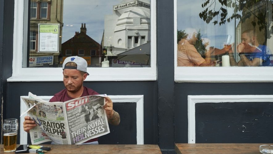 Un homme lit, le 18 juillet 2015 à Londres, le journal The Sun, qui a publié des images montrant la future reine Elizabeth II dans les années 1930, alors âgée d'environ six ans, faisant le salut nazi