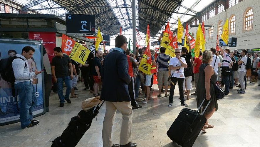 Quelques passagers passent devant les cheminots en grève, le 17 juin 2014 à la gare Saint-Charles de Marseille