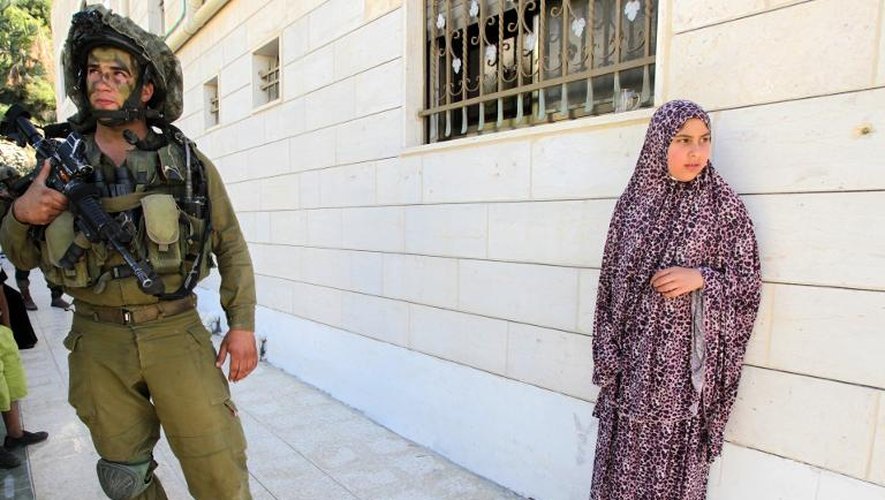 Une Palestienne et un soldat isréalien pendant la fouille de sa maison à Hébron, dans la bande de Gaza, dans le cadre de la recherche de trois adolescents israéliens disparus