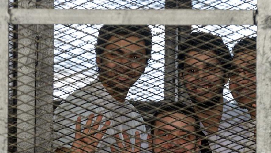 Des prisonniers accusés de liens avec les Frères musulmans dans le box grillagé du tribunal du Caire en Egypte parmi lesquels figurent trois journalistes d' Al-Jazeera le 22 avril 2014