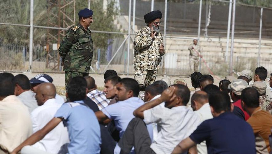 Des fidèles chiites irakiens écoutent les ordres de leurs supérieurs avant de s'engager comme volontaires pour combattres les membres de l'EIIL, le 18 juin 2014 à Kerbala