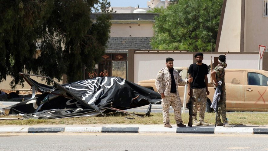 Des membres des forces gouvernementales libyennes près d'un drapeau du groupe jihadiste Etat islamique, le 10 juin 2016 à Syrte