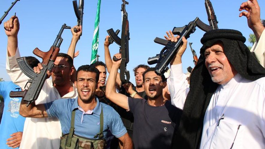 Des Irakiens volontaires pour combattre les jihadistes brandissent leurs armes, le 18 juin 2014 à Basra, dans le sud de l'Irak