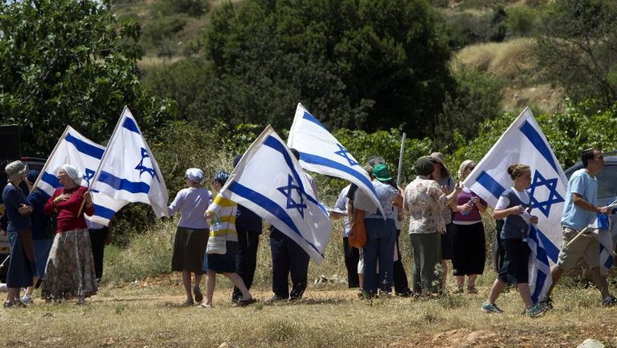 Des colons agitent le drapeau de l'Etat hébreu près du village arabe de Al-Khader en Cisjordanie, le 24 mai 2013