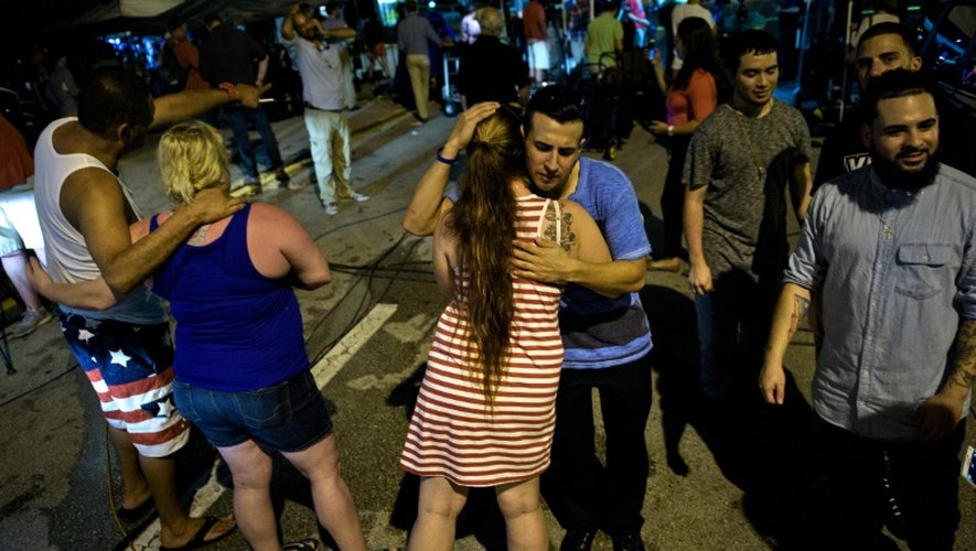 Des anonymes se réconfortent après avoir prié devant la boite de nuit Pulse le 12 juin 2016 à Orlando