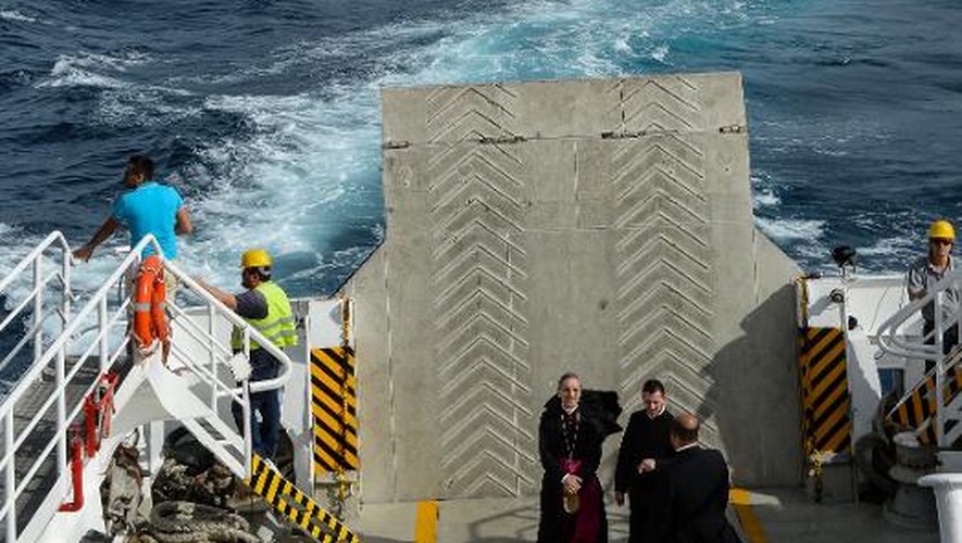 Des hommes d'église sur un ferry, à proximité de l'épave du navire de croisière Costa Concordia, échoué en janvier 2012 près de la petite île toscane du Giglio, le 15 septembre 2013
