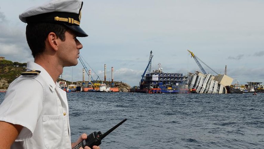Un officier de marine italien observe l'épave du navire de croisière Costa Concordia, échoué en janvier 2012 près de la petite île toscane du Giglio, le 15 septembre 2013