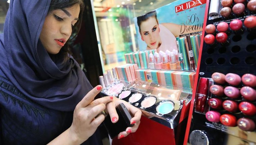 Porter du maquillage ni viole pas les lois de la République islamique qui oblige les femmes à être voilées. Ici une femme choisit une ombre à paupières dans un magasin de Téhéran, le 6 mai 2014