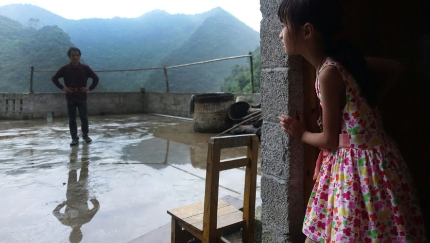 Meng Yiping, qui vit avec ses grands parents, parle avec son oncle dans sa maison à Longfu, dans la région autonome du Guangxi, le 19 juin 2015