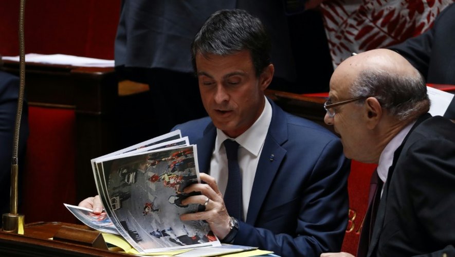 Le Premier ministre Manuel Valls et le secrétaire d'Etat des Relations avec le Parlement Jean-Marie Le Guenavec des photos de la manifestation contre la loi travaik, le 15 juin 2016 à l'Assemblée nationale à Paris