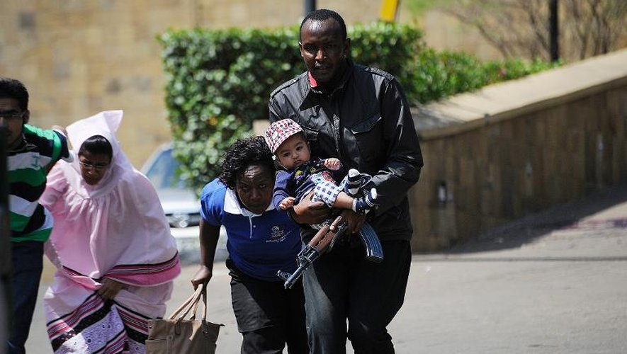 Un policier escorte des personnes qui quittent un centre commercial de Nairobi, dans lequel se déroule une prise d'otages, le 21 septembre 2013