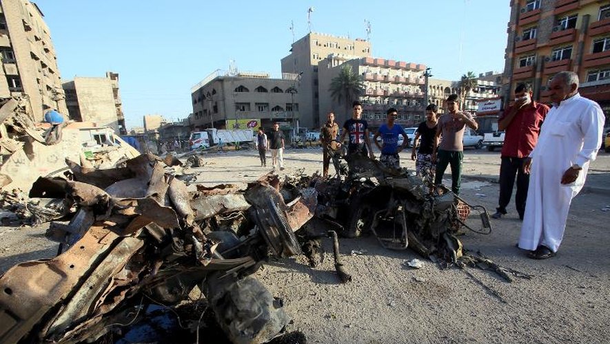 Des Irakiens devant les débris d'une voiture piégée le 18 septembre 2013 à Bagdad