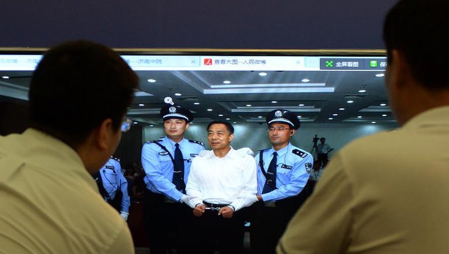 Des personnes regardent sur un écran l'ex-dirigeant chinois Bo Xilai, condamné à la prison à vie après son procès à Jinan, le 22 septembre 2013