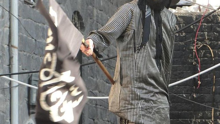 Image fournie par le réseau syrien Shaam News Network montrant un militant syrien agitant le drapeau des jihadistes islamistes à Homs, le 8 août 2013