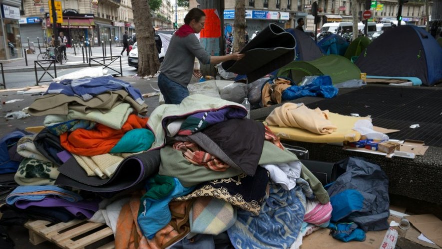 Des bénévoles récupèrent les tentes en bon état lors de l'évacuation d'un campement de migrants le 16 juin 2016 à Paris