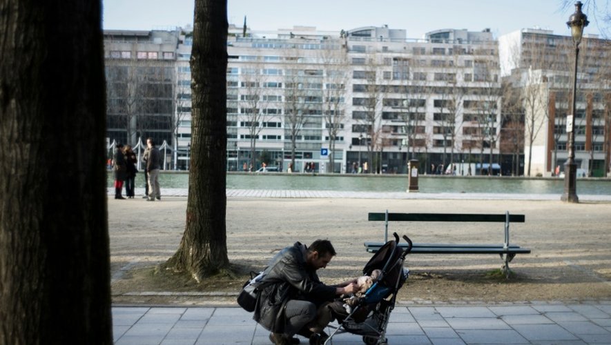 Un homme s'occupe de son enfant au cours d'une balade dans les rues de Paris, le 20 février 2013