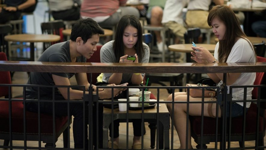 Des amis sont penchés sur leur smartphone, le 19 mars 2013 dans un café à Bangkok