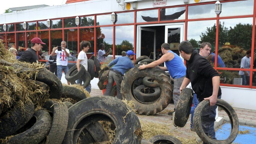 Des agriculteurs déchargent du foin et des pneus devant l'entrée d'un restaurant Buffalo Grill à Metz, le 28 juillet 2015