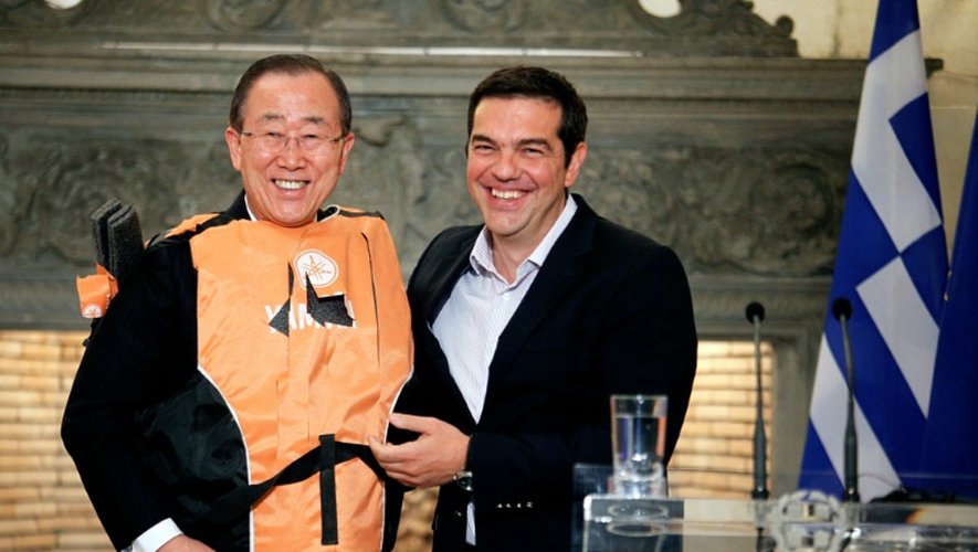 Le secrétaire général de l'ONU Ban Ki-moon (g) en gilet de sauvetage offert par le Premier ministre grec Alexis Tsipras (d) comme un  "symbole" des traversées périlleuses des migrants, le 18 juin à Athènes