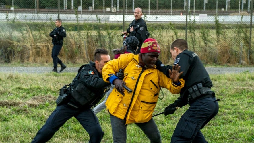 Des gendarmes français arrêtent un migrant, à Coquelles près de Calais, le 29 juillet 2015