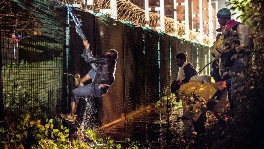 Des migrants tentent de grimper un mur du terminal de l'Eurotunnel à Coquelles, près de Calais, le 30 juillet 2015