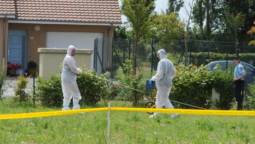 Des enquêteurs inspectent le jardin autour de la maison où 3 corps ont été retrouvés et deux blessés, le 26 juin 2014 à Claville