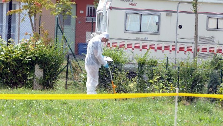 Un enquêteur relève des empreintes dans le jardin de la maison de Claville, le 26 juin 2014 où trois corps et deux personnes gravement blessées ont été retrouvés
