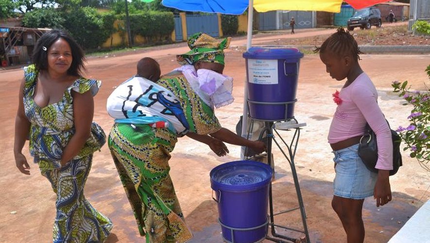 Des femmes se lavent les mains, le 25 juin 2014, à l'entrée de l'hopital de Kipe en Guinée, alors que l'épidémie d'Ebola est considérée comme "hors de contrôle" dans certains pays d'Afrique de l'ouest