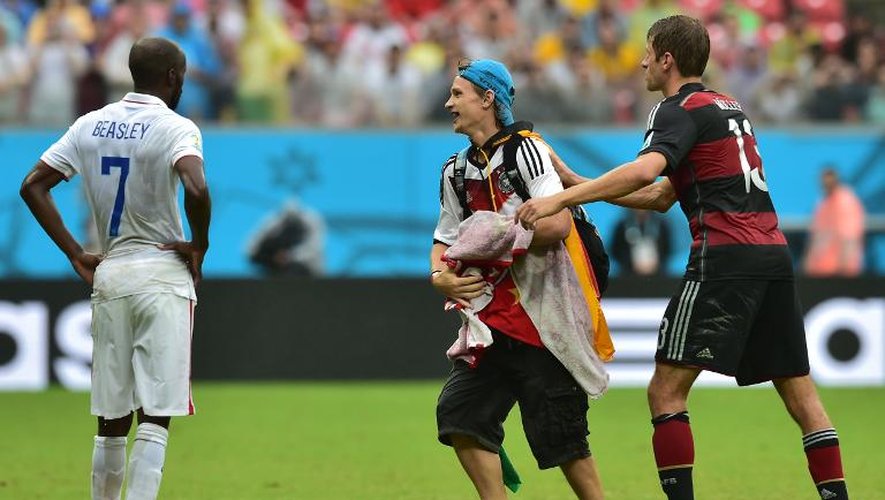 Le défenseur américain DaMarcus Beasley (g) regarde Thomas Müller (d) qui salue un fan allemand lors de leur match au Mondial, le 26 juin 2014 à Recife