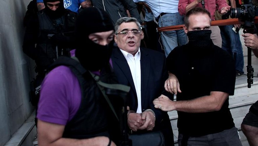 Nikos Michaloliakos entouré de policiers masqués à la sortie des locaux de la police le 28 septembre 2013 à Athènes