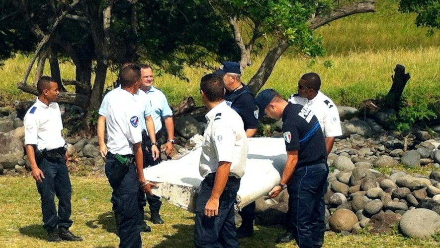 Des policiers transportent le débris d'avion retrouvé sur la côte de Saint-André de la Réunion, le 29 juillet 2015