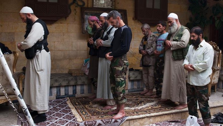 Abou Mohammed (g), un imam sunnite aumônier de la brigade Liwa al-Tawhid, proche des Frères musulmans, prie avec ses camarades, le 18 septembre 2013 à Alep, en Syrie