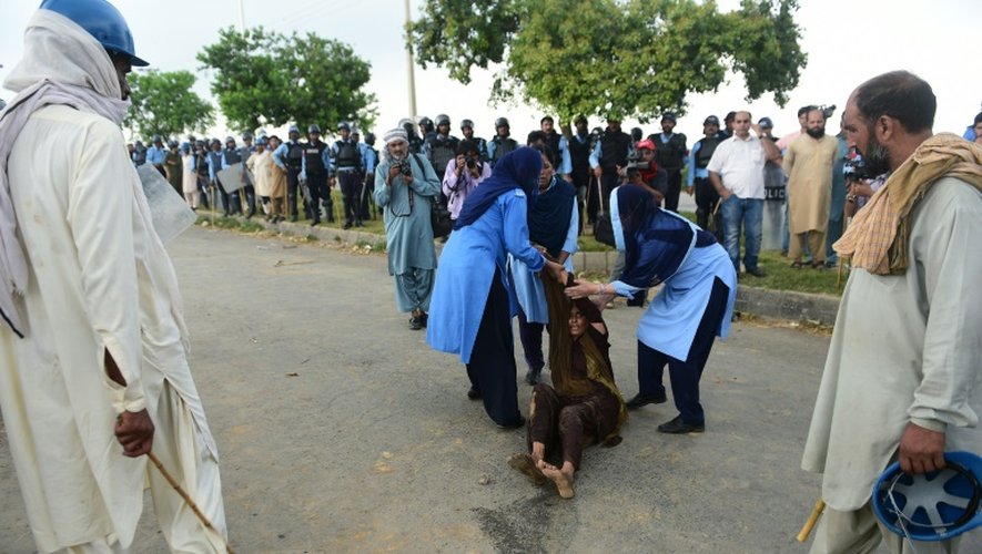 Deux policières pakistanaises procèdent à l'arrestation d'une habitante du "ghetto afghan" d'Islamabad, le 30 juillet 2015, avant la démolition de ce vaste bidonville