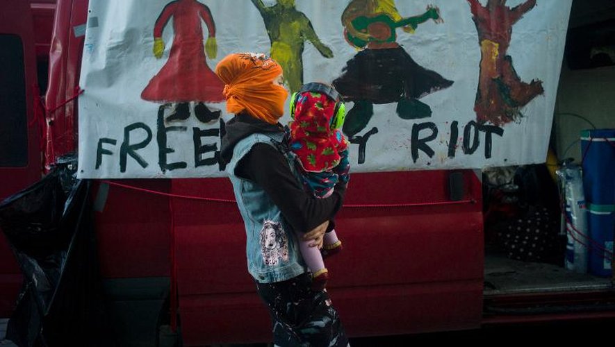 Une mère cagoulée et son bébé passe devant une camionnette réclamant la libération des Pussy Riot lors d'une manifestation à Prague le 28 septembre 2013