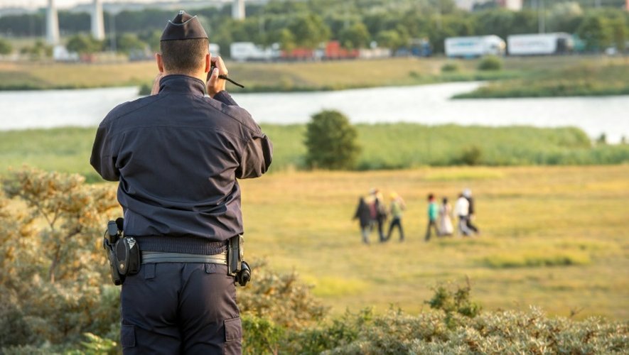 Un gendarme filme des migrants qui tentent de pénétrer sur le site d'Eurotunnel pour atteindre le Royaume-Uni à Coquelles près de Calais, le 31 juillet 2015